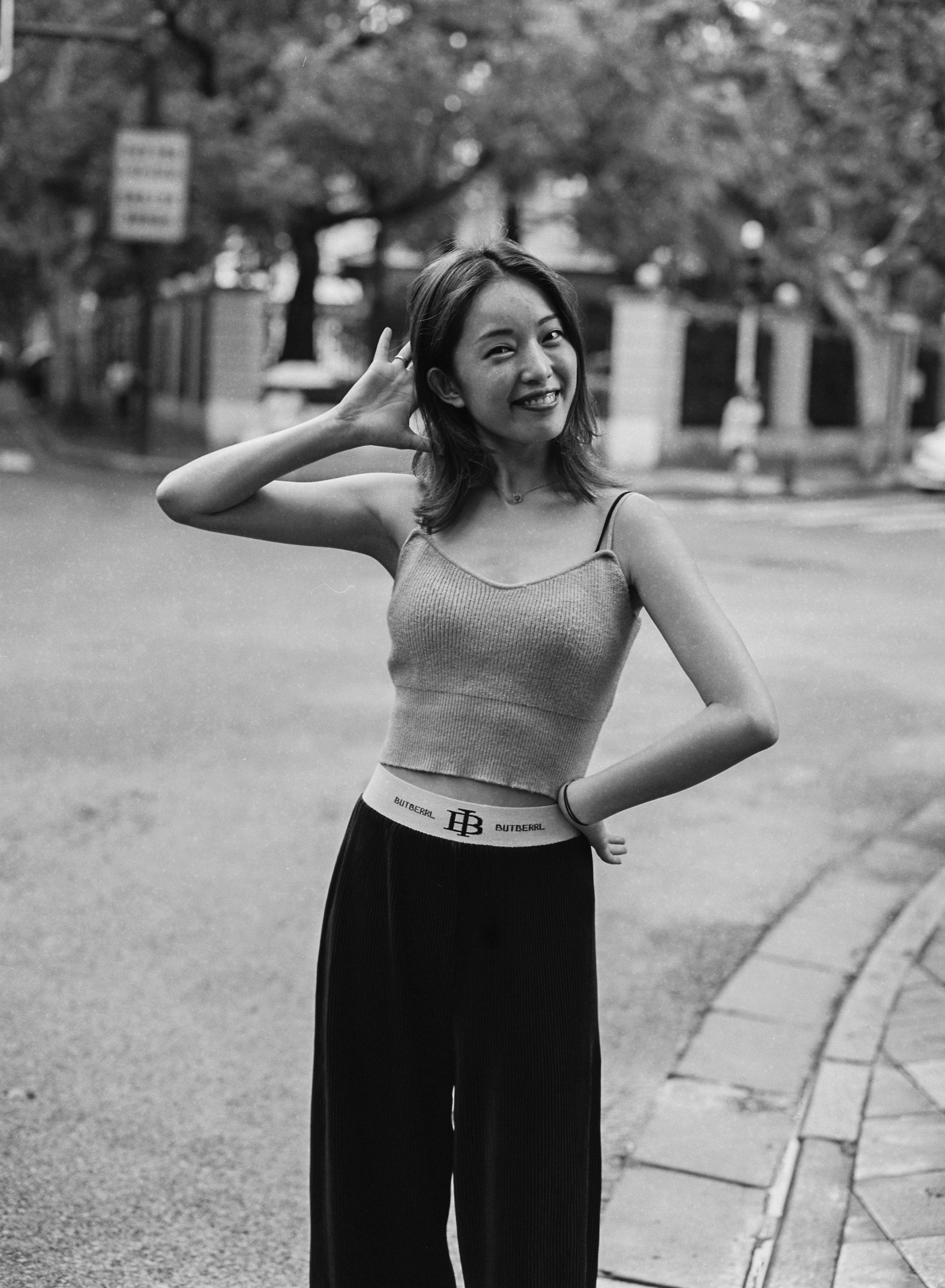 woman in spaghetti strap top and black skirt standing on sidewalk during daytime